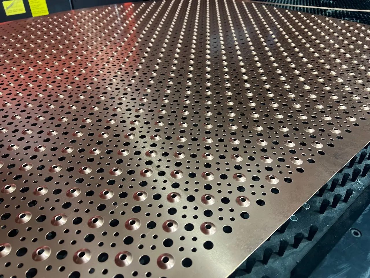 A laser-cut perforated metal panel on the cutting bed