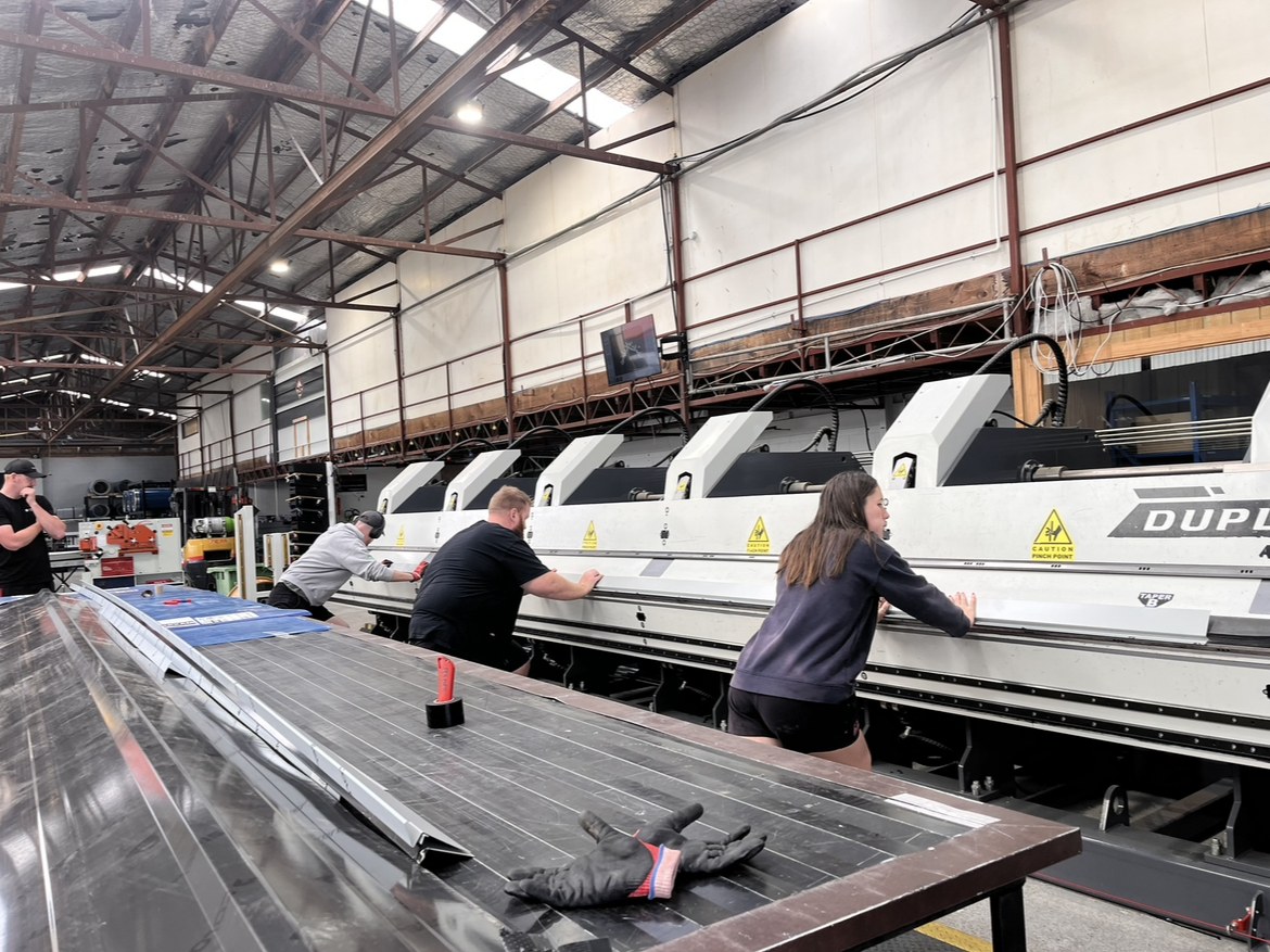 The Linked Group team running a roofing panel through the production line
