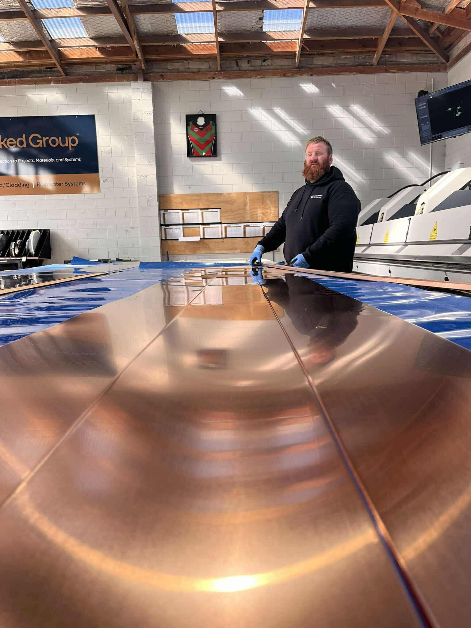 A Linked Group fabricator preparing a copper cladding sheet in the Matamata workshop