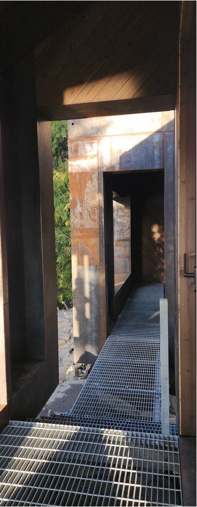 A corten-clad passage with grated flooring