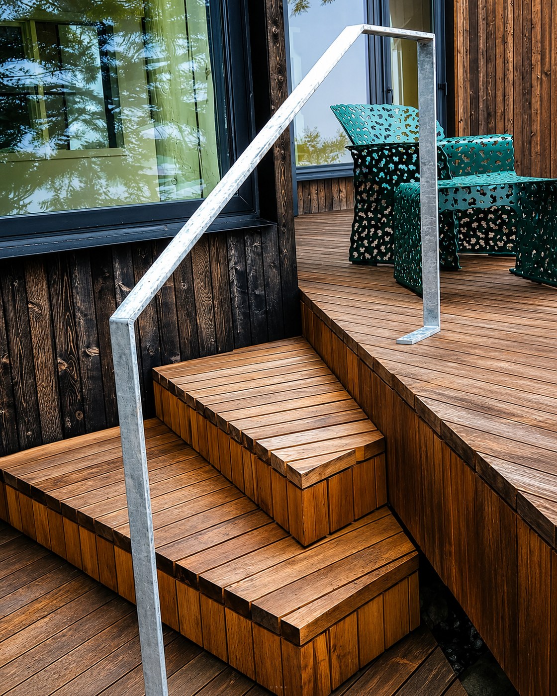 A galvanized handrail beside timber steps