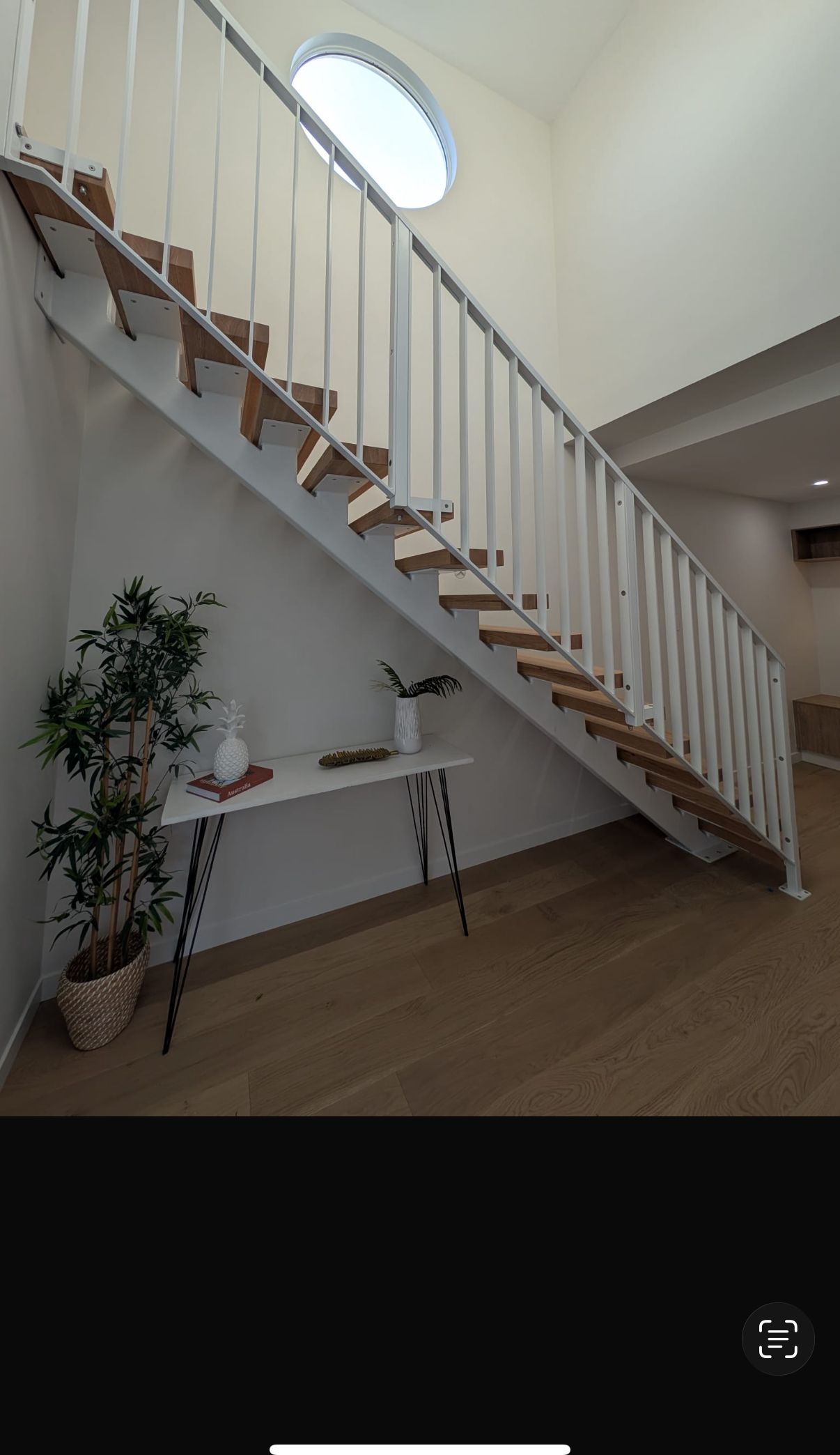 An interior steel-stringer staircase with timber treads and a white steel balustrade