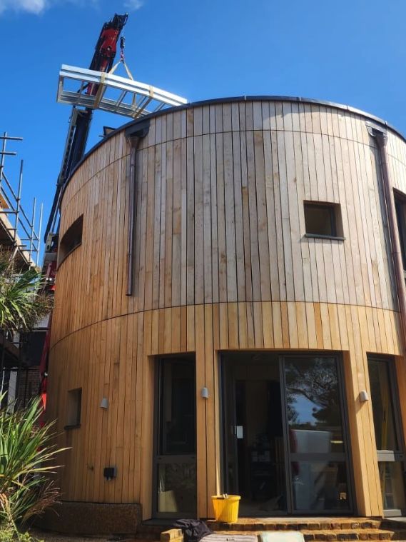 A curved, timber-clad building under construction